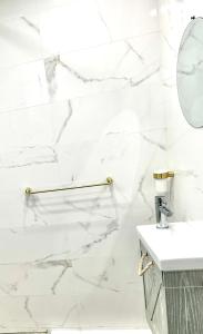 a white marble bathroom with a sink and mirror at Le studio du voyageur in Saint-Denis