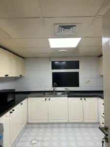 uma cozinha com armários brancos e um lavatório em CareforU Hostel Al mankhool Burjman metro em Ghantoot