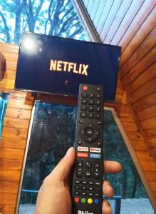 a person holding a remote control in front of a netflix box at ECO PARK ALTA MIRA in São Francisco de Paula