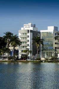 een groot gebouw met palmbomen voor een waterlichaam bij Hotel Atlas in Sete Lagoas