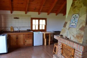 a kitchen with white appliances and a brick fireplace at Posada Tajaluz in Río Pico