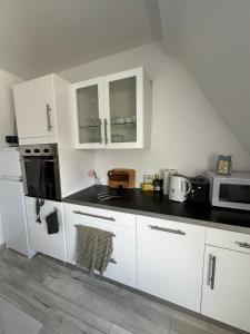 a kitchen with white cabinets and a black counter top at Komplette 3 Zimmer Wohnung Heidelberg in Leimen