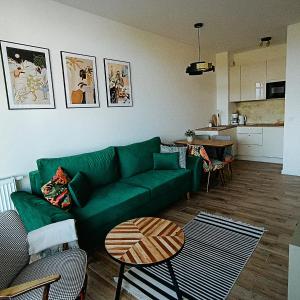 uma sala de estar com um sofá verde e uma cozinha em Apartament Tropikalny prywatny taras na dachu z widokiem na morze em Sianozety