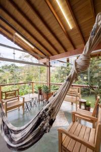 een hangmat in een kamer met stoelen en tafels bij Casa de Campo com lazer , pássaros e muito verde. in Poços de Caldas