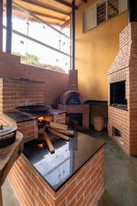 een grote keuken met een bakstenen oven en een grill bij Casa de Campo com lazer , pássaros e muito verde. in Poços de Caldas