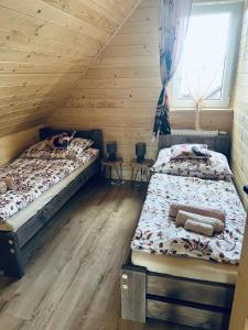 two beds in a room with wooden walls at Domek RajskiRaj in Rajcza