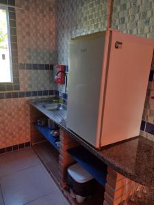 eine Küche mit einer Spüle und einer Theke mit einem Kühlschrank in der Unterkunft Casa Girassol in Itaparica Town