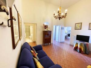 a living room with a blue couch and a chandelier at Appartamento Mimosa in Siena