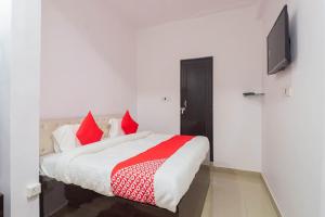 a bedroom with a bed with red pillows and a tv at OYO Royal Inn Near Phoenix United Lucknow in Charbagh