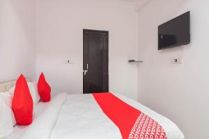 een slaapkamer met een bed met rode kussens en een televisie bij SPOT ON Royal Inn in Charbagh