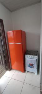uma cozinha com um frigorífico laranja e um fogão em Os Passarinhos B.I. em Barra de Ibiraquera