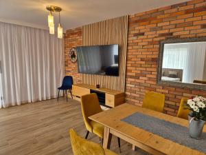 a living room with a dining room table and a brick wall at Wypoczynek nad zatoką Apartamenty Władysławowo in Władysławowo