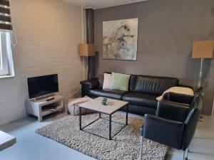 a living room with a black leather couch and a table at Vakantiewoning Schouwenberg in Swalmen