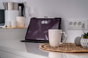 a laptop computer sitting on a counter with a coffee cup at Marion Cozy Rooms in Ermoupoli