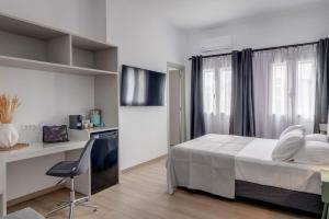 a bedroom with a bed and a desk with a computer at Marion Cozy Rooms in Ermoupoli