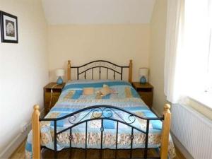 a bedroom with a bed with a blue comforter at The Gardener's Cottage in Ballymote