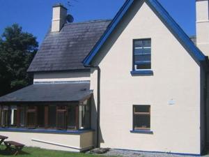 uma casa branca com um telhado azul e um banco em The Gardener's Cottage em Ballymote
