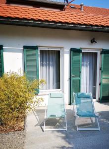 two chairs sitting outside of a house with green shutters at Aparthotel "Goldener Hahn Apartments" in Bad Waltersdorf