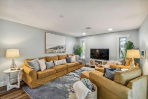 a living room with couches and a flat screen tv at Luxury heated-pool home blocks from the beach in Tarpon Springs