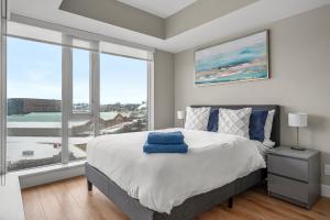 a bedroom with a large bed and a large window at UPDATED! Downtown, Near Saddledome, Stampede & Casino! FREE Banff Pass, Gym & Parking! in Calgary