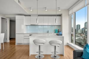 a kitchen with white cabinets and a bar with stools at Walk to Bars, Casino, Stampede & Saddledome PLUS FREE Bonus Banff Pass, Parking & Wine! in Calgary