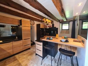 una cocina con una isla con 2 sillas y una barra en La Noz Vad, Superbe maison Perigourdine, en Saint-Cybranet