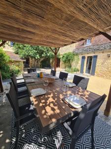 een houten tafel en stoelen onder een houten parasol bij La Noz Vad, Superbe maison Perigourdine in Saint-Cybranet