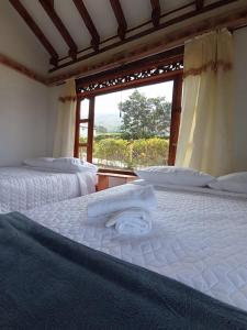 two beds in a room with a window at TerraZen Cabaña Privada in Villa de Leyva
