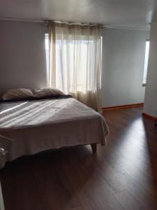 um quarto com uma cama e uma janela com cortinas em casa Galilea em Rancagua