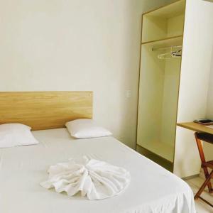 Un dormitorio con una cama blanca con una toalla. en PRINCIPE HOTEL, en Sorriso