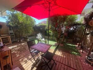 einen Tisch und einen roten Regenschirm auf einer Terrasse in der Unterkunft Cannes Cosy Oasis in Cannes