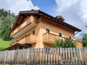 una casa con balcones de madera en la parte superior de una valla en B&B B&Beautyfol Dolomites adults only, en Predazzo