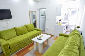 a living room with a green couch and a table at Central Vista Apartments Sarajevo in Sarajevo