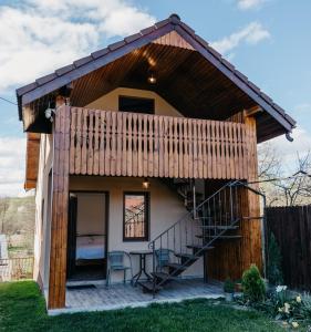 a small house with a balcony and a table at EDANT HOUSE in Bumbesti Pitic