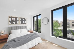 a white bedroom with a bed and large windows at 149BK-501 NEW Prime greenpoint 2BR WD in unit in Brooklyn