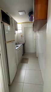 a small kitchen with a refrigerator and a stove at Apartamento Pé na Areia - Praia Grande in Praia Grande