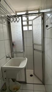 a white bathroom with a sink and a shower at Apartamento Pé na Areia - Praia Grande in Praia Grande