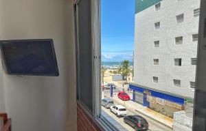 a window with a view of a street and a building at Apartamento Pé na Areia - Praia Grande in Praia Grande