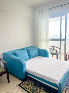 Sofá azul en la sala de estar con ventana en Pérola do Aquarius III, en São José dos Campos