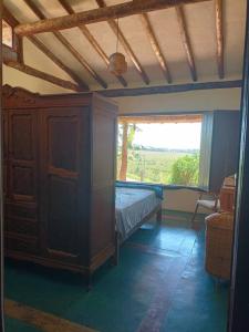 een slaapkamer met een bed en een groot raam bij Casa rústica com piscina - SJC in Eugênio de Melo