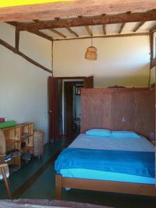 Schlafzimmer mit einem blauen Bett und einem Kopfteil aus Holz in der Unterkunft Casa rústica com piscina - SJC in Eugênio de Melo