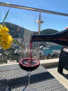 une bouteille de vin servie dans un verre de vin dans l'établissement Apartments ORCHIDEA 1, à Dubrovnik