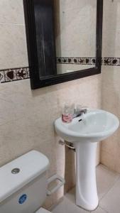 een badkamer met een wastafel, een toilet en een spiegel bij Apto 3 alcobas, Segundo piso Norte de Cali in Cali