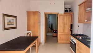 cocina con armarios de madera y encimera negra en Modern Private Rooms in an apartment, en St Paul's Bay