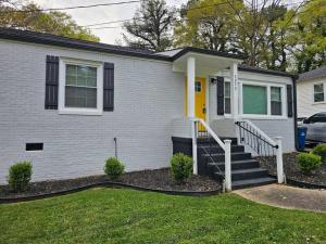 Casa blanca con puerta amarilla y escaleras en Tranquil Retreat: Short-Term Luxury Rental en Atlanta