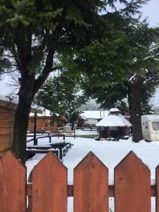 a fence covered in snow next to a tree at Mapunre in Malalcahuello