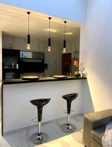 a kitchen with a bar with two stools at Beach House Praia de Carapibus in Jacumã