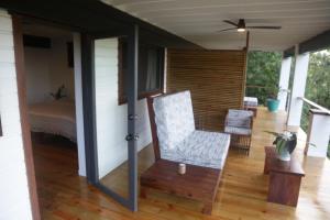 eine Veranda eines Hauses mit einem Stuhl und einem Bett in der Unterkunft Roam Yoga & Wellness Lodge in Bocas del Toro