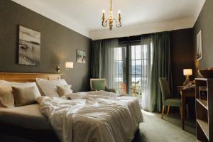 a bedroom with a bed and a desk and a window at Hotel Villa Rainer in Pörtschach am Wörthersee