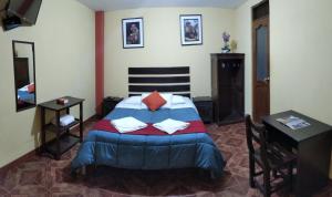 a bedroom with a bed and a table and a mirror at Hospedaje Del Carmen in Machu Picchu